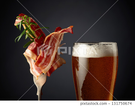 Beer and slices of  fried bacon with rosemary. 131750674