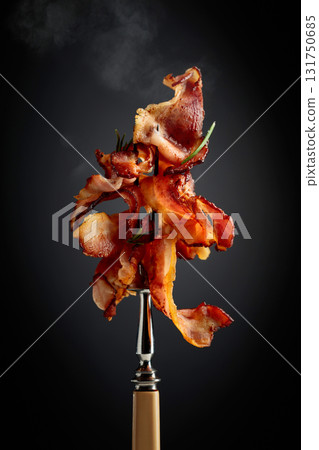 Fried bacon with rosemary on a fork. 131750685