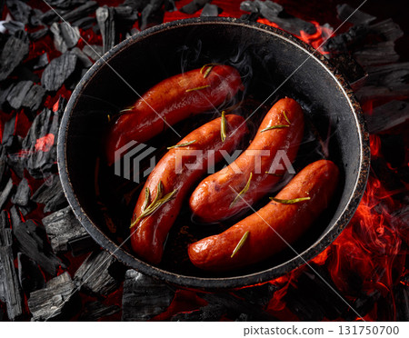 Roasted Bavarian sausages with rosemary on a burning charcoal. 131750700