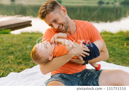 Father Playing With Baby On Picnic Blanket 131751510