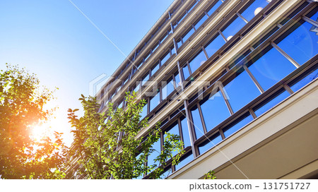 Glass office building surrounded with green trees.  Eco-friendly office building. Sustainable architecture of city reducing heat carbon dioxide modern city environment. 131751727