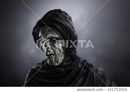 Portrait of a zombie with hooded cape over dark misty background 131752058