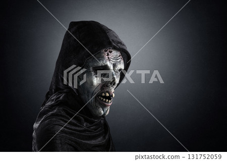Portrait of a zombie with hooded cape over dark misty background 131752059