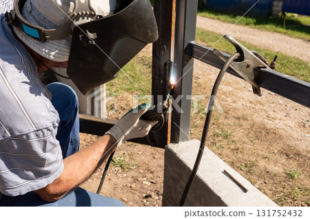 Male welder working on metal frame construction outdoors. National Welding Month Male welder working on metal frame construction outdoors. National Welding Month 131752432