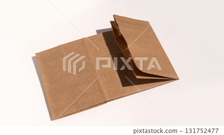 Brown kraft paper bag lying flat on neutral background with sunlight Brown kraft paper bag lying flat on neutral background with sunlight 131752477
