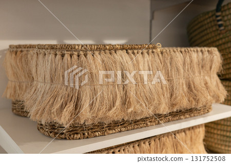 Handwoven fringe basket on white shelf with fiber texture and natural design 131752508
