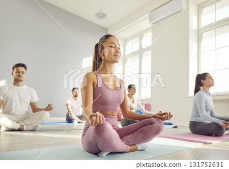 Woman Meditating in Lotus Pose Amidst Yoga Group 131752631
