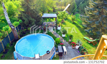 Garden of a suburban house in summer in which you can see a removable swimming pool, pergola in a place with a lot of vegetation. 131752702