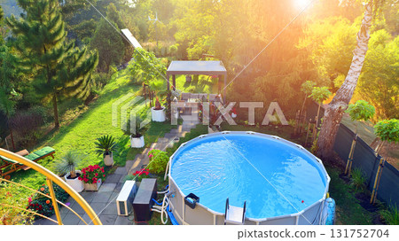 Garden of a suburban house in summer in which you can see a removable swimming pool, pergola in a place with a lot of vegetation. Garden of a suburban house in summer in which you can see a removable swimming pool, pergola in a place with a lot of vegetation. 131752704