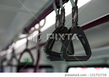 Close up photograph showing triangular hand straps hanging from ceiling, typical in modern train interior, with minimalistic lighting and clean design Close up photograph showing triangular hand straps hanging from ceiling, typical in modern train interior, with minimalistic lighting and clean design 131752739