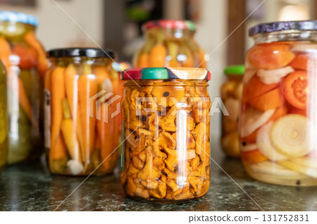 Variety of colorful pickled vegetables in glass jars on kitchen counter. National Pickle Day Variety of colorful pickled vegetables in glass jars on kitchen counter. National Pickle Day 131752831