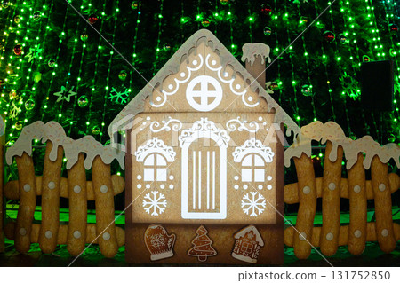 Festive gingerbread house with christmas decorations and illuminated green background Festive gingerbread house with christmas decorations and illuminated green background 131752850