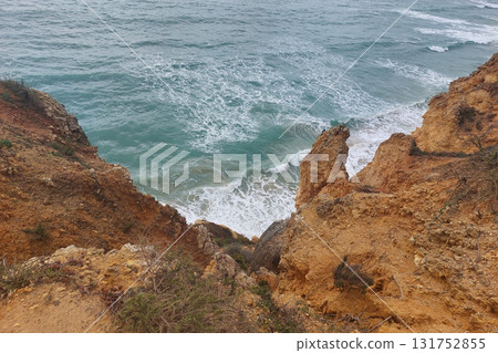 Rugged coastal cliffside overlooking turquoise ocean waves 131752855