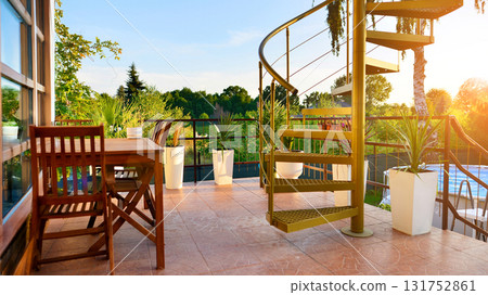 Steel spiral gold staircase on the terrace with plants and plants in pots background. Steel spiral gold staircase on the terrace with plants and plants in pots background. 131752861