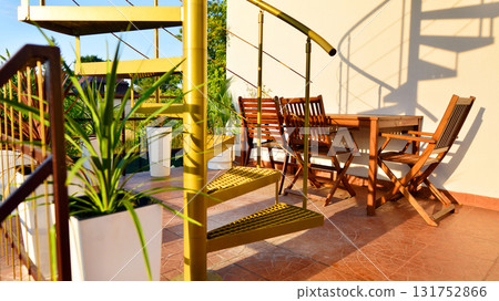 Steel spiral gold staircase on the terrace with plants and plants in pots background. 131752866