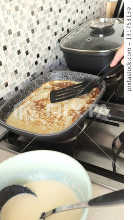 Anonymous person fries pancake in rectangular nonstick pan. This homemade pancake is made in kitchen using organic, gluten-free ingredients. 131753139