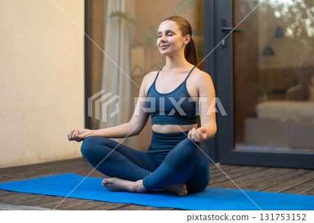 Young woman sitting in a lotus pose and meditating Young woman sitting in a lotus pose and meditating 131753152