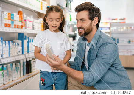 Male parent with beard and daughter inside modern pharmacy Male parent with beard and daughter inside modern pharmacy 131753237