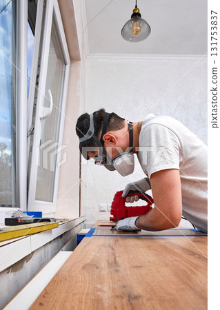 repairman using electric handheld jigsaw and cutting hole for the sink in the kitchen countertops repairman using electric handheld jigsaw and cutting hole for the sink in the kitchen countertops 131753837