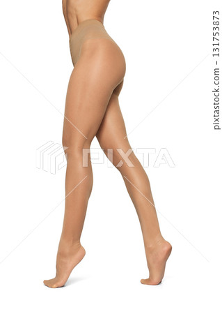 Beautiful long fit female legs in beige tights on white background Beautiful long fit female legs in beige tights on white background 131753873