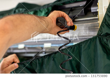 male hand of worker from the cleaning service cleans the air conditioner by spraying water, close-up male hand of worker from the cleaning service cleans the air conditioner by spraying water, close-up 131753890