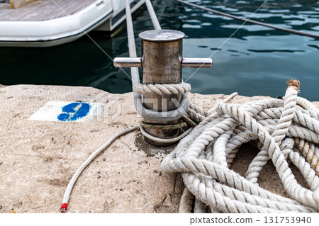Ropes tied to metal bollard on marina pier 131753940