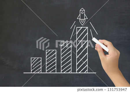 一個孩子的手畫了一個帶有火箭的向上傾斜的條形圖 - 一幅提高成績和學術能力的圖像 131753947