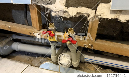 New plastic pipes with plugs in an apartment against the background of damaged tiles 131754441