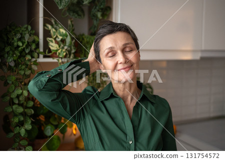 Satisfied mature woman enjoying short haircut at home running hand through hair, senior slow life Satisfied mature woman enjoying short haircut at home running hand through hair, senior slow life 131754572