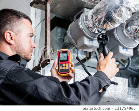 Technician use hand-held anemometer measuring air flowing measurement. 131754965