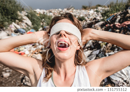 A blindfolded female volunteer screams from powerlessness in a dump of plastic  131755312