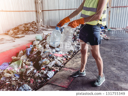 Woman-volunteer sorting trash at modern recycling plant. Woman-volunteer sorting trash at modern recycling plant. 131755349