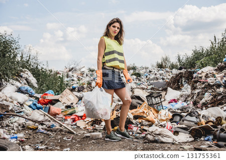 Woman volunteer helps clean the field of plastic garbage.  131755361