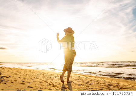 Beautiful woman at the windy spring day relaxing on coast. Carefree lady looking at the sunset. Beautiful woman at the windy spring day relaxing on coast. Carefree lady looking at the sunset. 131755724