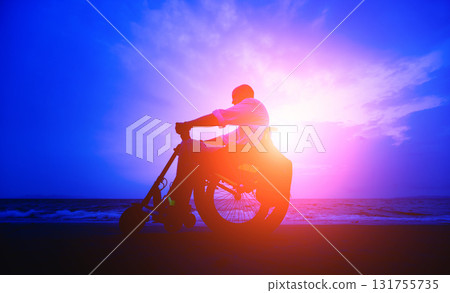 Disabled man in a wheelchair on the beach. Silhouette at sunset. Disabled man in a wheelchair on the beach. Silhouette at sunset. 131755735