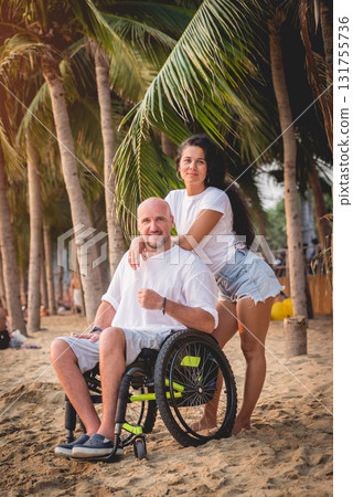 Disabled man in a wheelchair with his wife on the beach. Disabled man in a wheelchair with his wife on the beach. 131755736