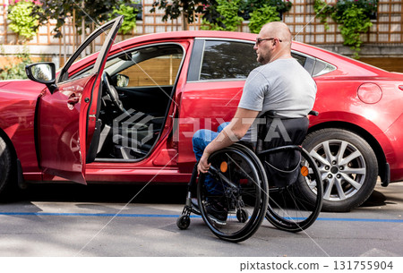Young handicapped driver getting in red car fom wheelchair Young handicapped driver getting in red car fom wheelchair 131755904
