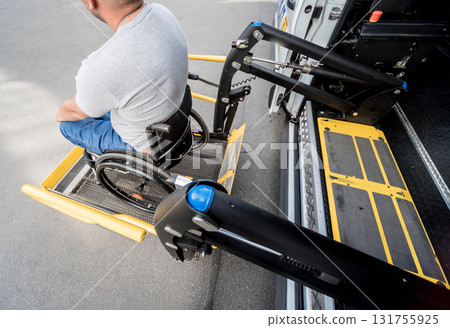 A man in a wheelchair on a lift of a vehicle for people with disabilities A man in a wheelchair on a lift of a vehicle for people with disabilities 131755925