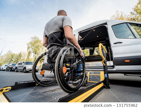 A man in a wheelchair moves to the lift of a specialized vehicle A man in a wheelchair moves to the lift of a specialized vehicle 131755962