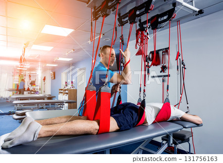 Physiotherapy. Suspension training therapy. Young man doing fitness traction 131756163