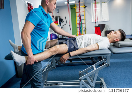 Rehabilitation therapy. Physiotherapist working with young male patient Rehabilitation therapy. Physiotherapist working with young male patient 131756177