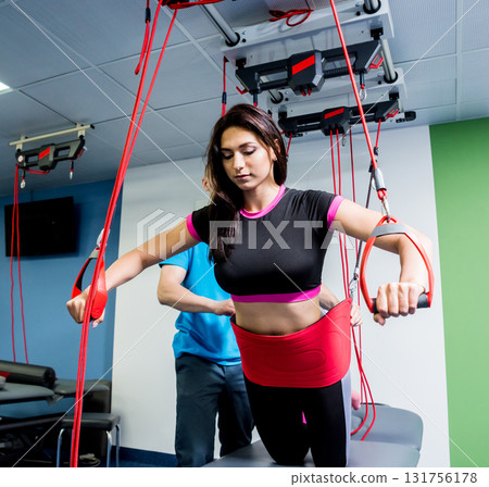 Physiotherapy. Suspension training therapy. Young woman doing fitness traction Physiotherapy. Suspension training therapy. Young woman doing fitness traction 131756178