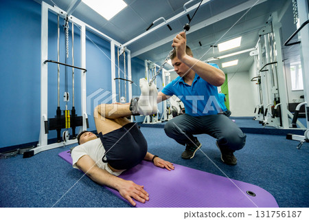 Rehabilitation therapy. Young man doing exercises on mat  131756187