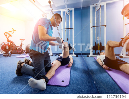 Rehabilitation therapy. Young man doing exercises on mat  131756194