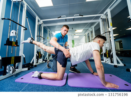 Rehabilitation therapy. Young man doing exercises on mat  131756196