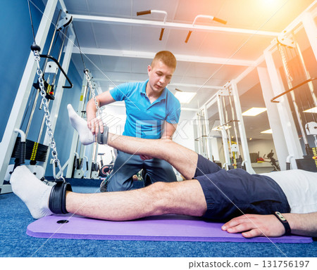 Rehabilitation therapy. Young man doing exercises on mat  131756197