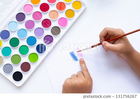 Child painting with watercolors on white paper with diverse color palette Child painting with watercolors on white paper with diverse color palette 131756267