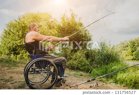 Handicapped man fishing at a lake. Wheelchair camping. 131756527