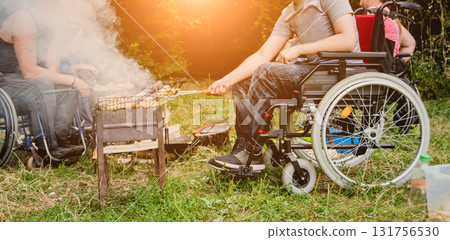 Disabled man resting in a campsite with friends. Wheelchair in the forest  131756530