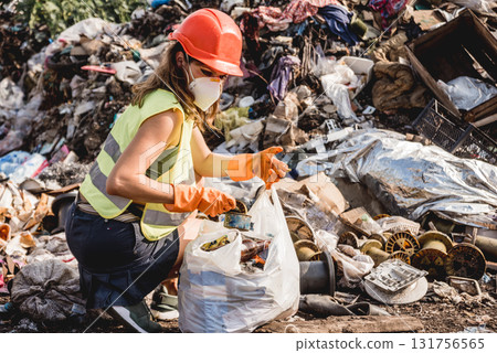 Woman volunteer helps clean the field of plastic garbage.  131756565
